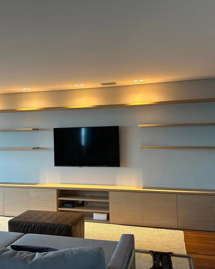 Painel de sala com prateleiras suspensas e rack planejado sob a TV